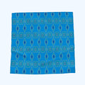 A square scarf with a geometric pattern of blue, teal, and light blue diamonds and ovals, laid flat against a white background.